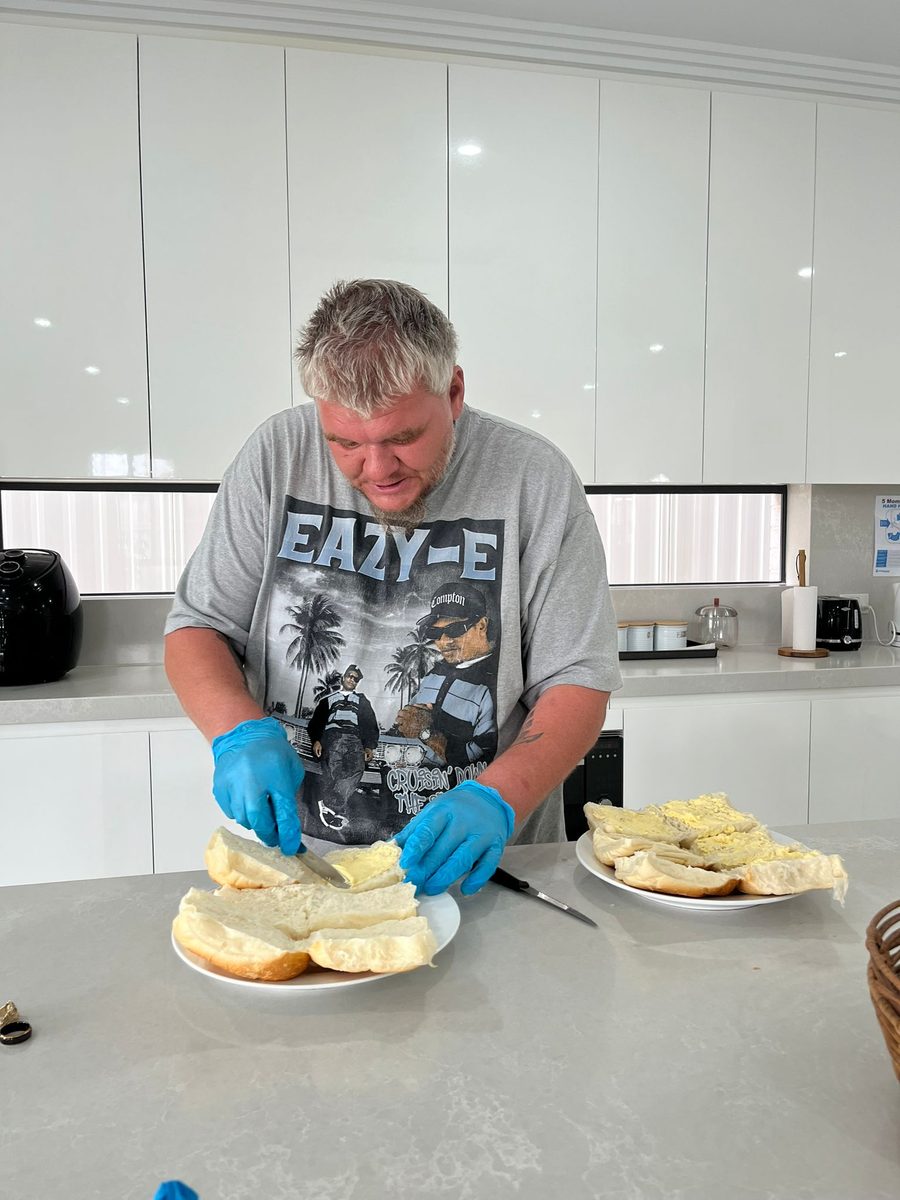 A resident preparing burgers in the kitchen at an ASDA home