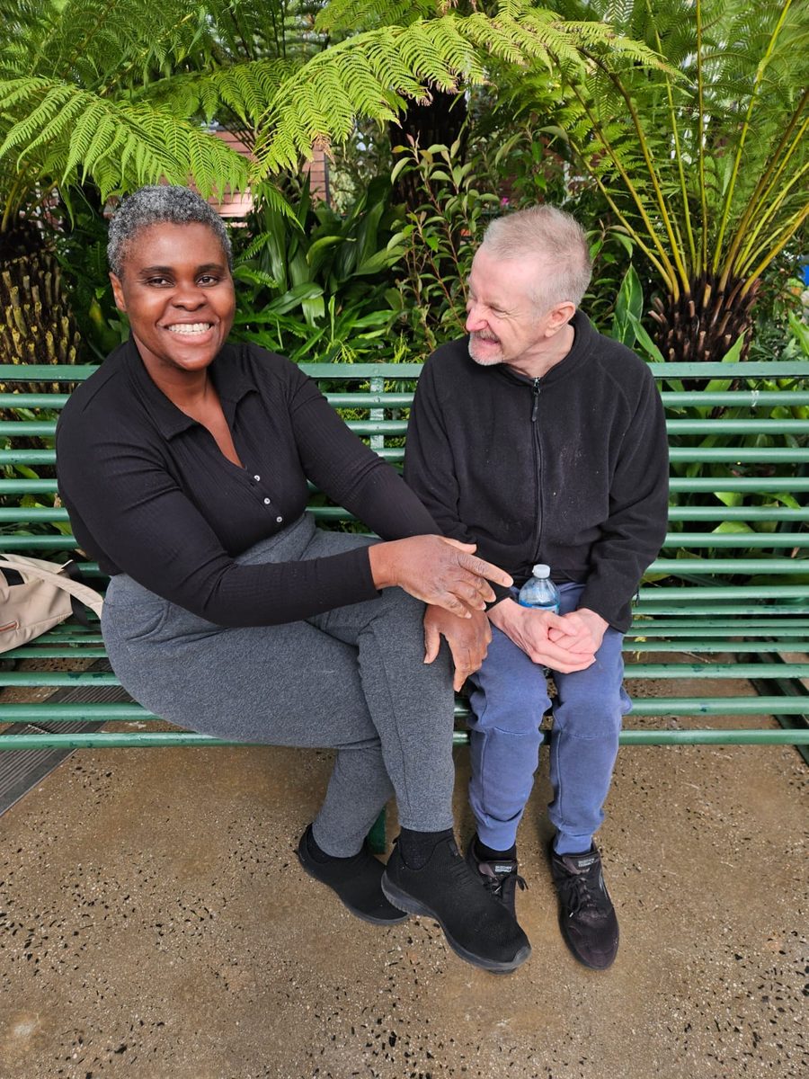 A support partner and resident sitting together in a garden